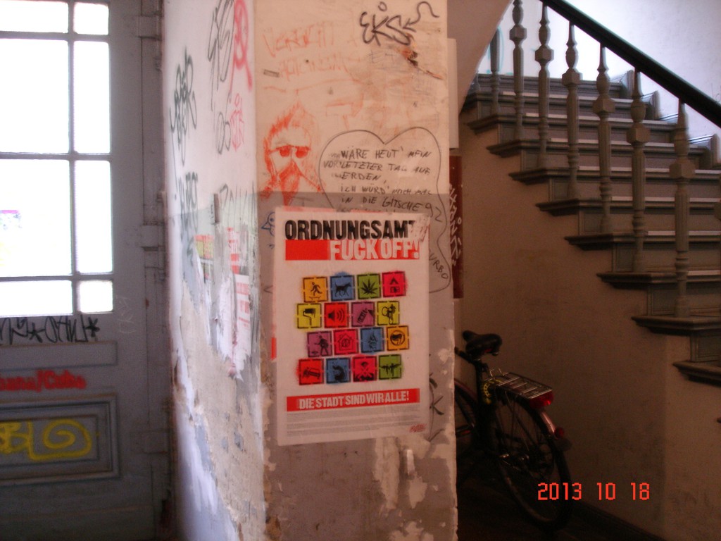 Ein Hausflur mit vielen Graffitis und einem Plakat: Ordnungsamt Fuck off