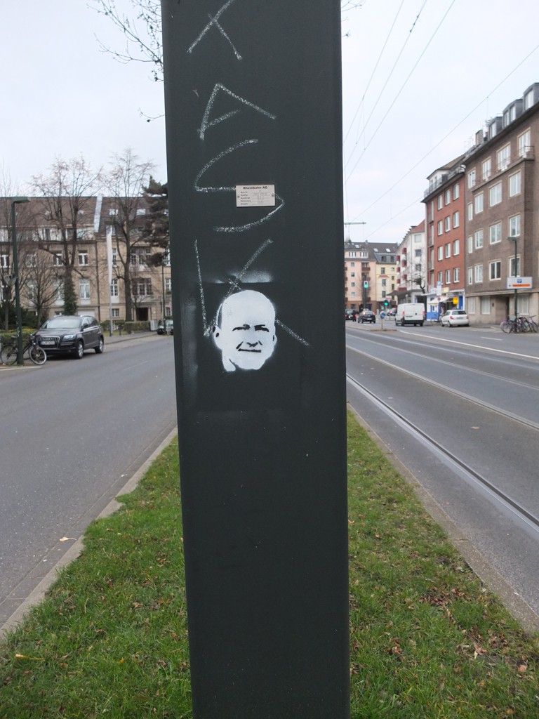 Street Art: Schablonenpostiv eines Gesichtes auf einem Strommast