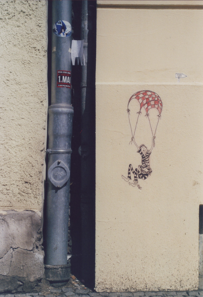 Street Art Daily Smile: Paste up eines Fallschirmspringers in Häftlingskleidung mit einem karierten Fallschirm